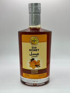 زجاجة عسل السدر الكشميري بحجم 500 غرام، تظهر الزجاجة الطويلة والأنيقة بلونها العنبري الغامق وملصق يحمل اسم المنتج ومنشأه